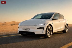 Pearl-white 2026 Tesla Model Y Juniper front three-quarter view at golden hour on a UAE highway shoulder, dunes in background