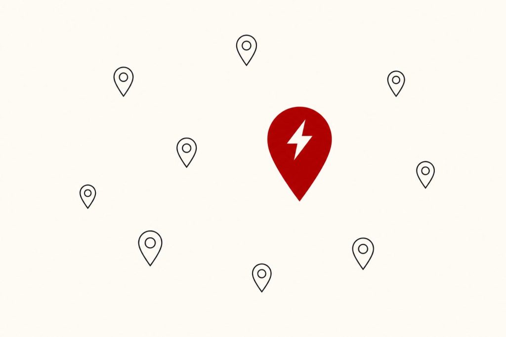 A cluster of charcoal map pins with one large red pin carrying a lightning bolt