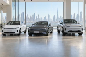 Three unbranded electric cars, a hatchback, a sedan and an SUV, in a showroom with the Dubai skyline behind