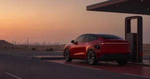 A red electric SUV charging beside a desert highway at dusk